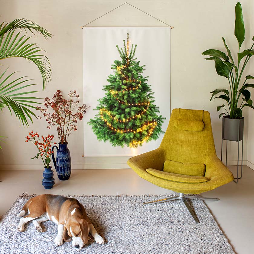 Kerstboom aan de muur groot 2 Duurzame kerstdecoratie voor bedrijven. Een prachtige feautuil met daarachter een kerstboom aan de muur. Op de voorgrond ligt een hondje.
