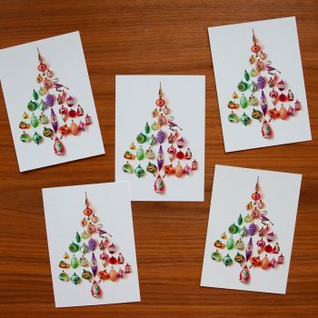 5 kerstkaarten gemaakt van kerstballen, liggend op tafel